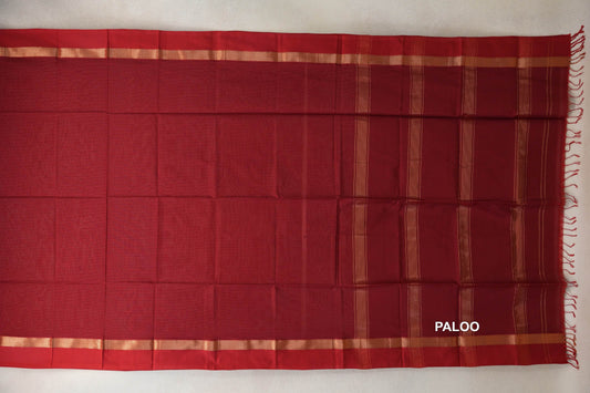 Deep red Maheshwari silk cotton saree spread flat, with narrow gold-toned borders and a striped pallu ending in red tassels.