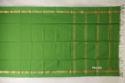 Leaf green Maheshwari silk cotton saree laid flat, with a plain body, gold-toned borders and a striped pallu with green tassels.