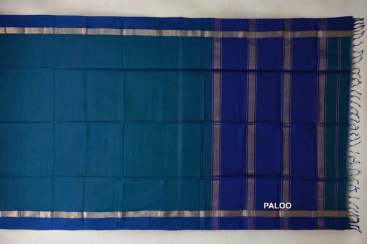 Peacock Blue Maheshwari silk cotton saree laid flat, with deep blue borders, silver-toned bands, a striped deep blue pallu and tassels.