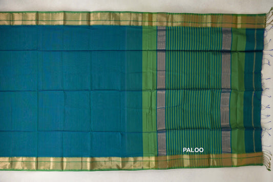 Maheshwari silk cotton saree laid flat, showing a peacock green body, leaf green and gold-toned borders, and a striped pallu with tassels.