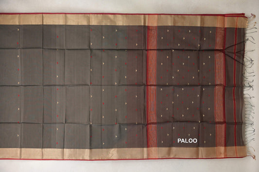 Charcoal grey Maheshwari silk-cotton saree spread flat, with small red and pale triangles, wide pale borders with deep red edging, and a fringed pallu.