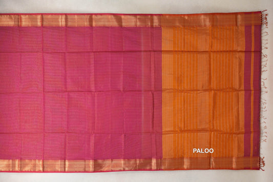 Rani pink Maheshwari silk cotton saree laid flat, showing a plain body, shimmering borders and an orange striped pallu with tassels.
