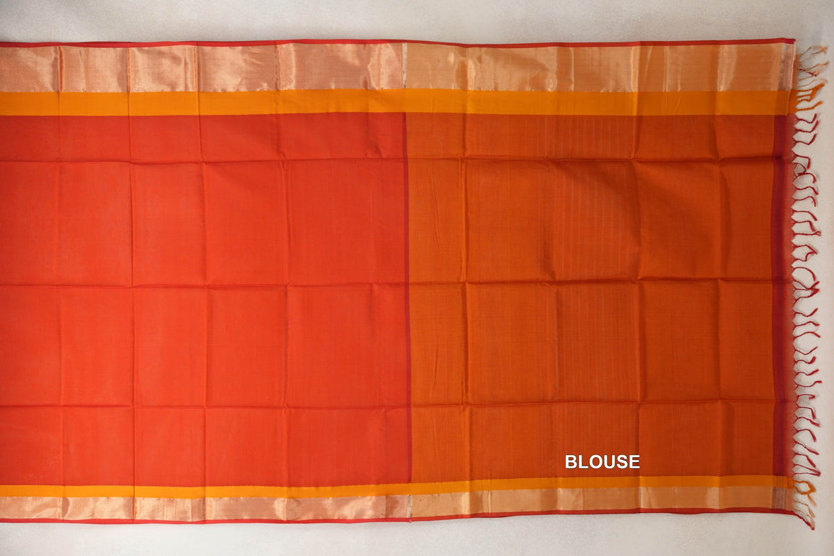 Laid-out tomato red Maheshwari silk cotton saree with mustard orange borders and red selvedge, alongside a mustard orange blouse panel with tassels.