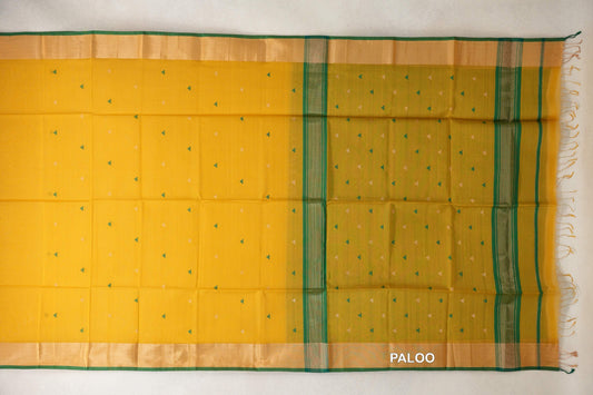 Turmeric yellow Maheshwari silk-cotton saree spread open, with small green and cream triangles, pale gold borders, and a striped pallu with tassels.