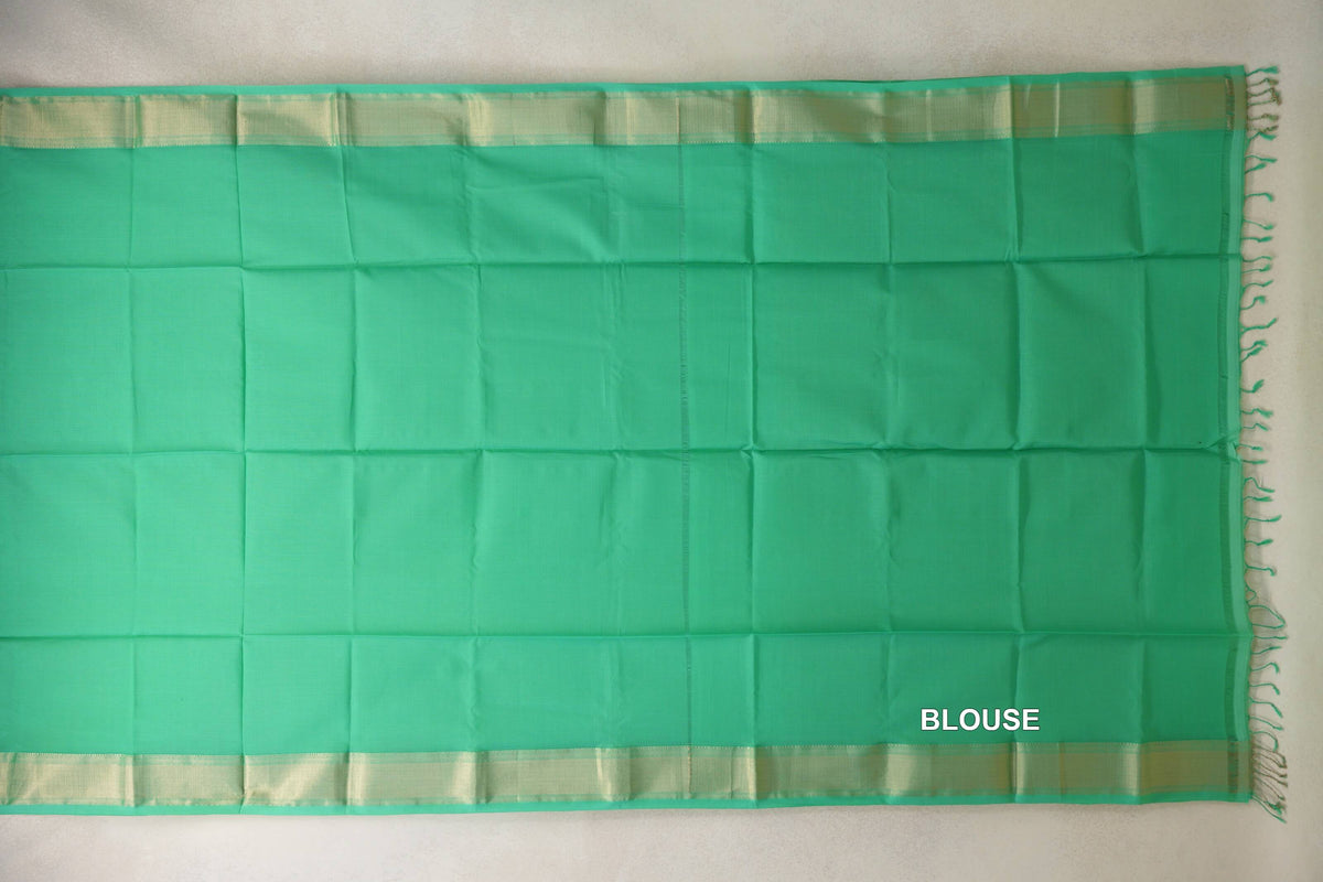 Sea green Maheshwari silk cotton blouse piece laid flat, with a plain body, pale gold-toned borders and tassels at one end.