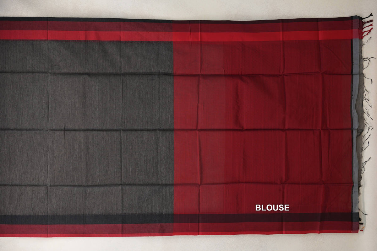Charcoal Grey Maheshwari silk cotton saree laid flat beside red blouse fabric, with red and dark striped borders and tassels at the edge.