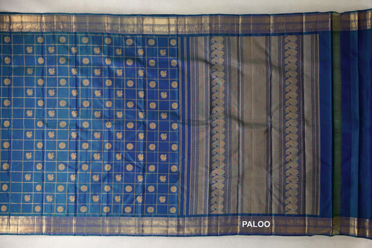 Peacock blue Kanjivaram silk saree laid open, showing a checked body with gold circles and small motifs, ornate borders and a striped pallu.