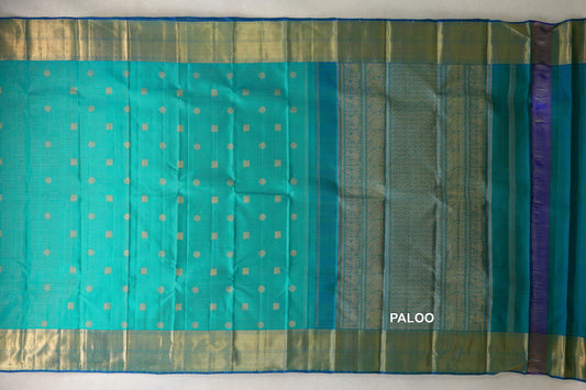 Aqua green Kanjivaram silk saree laid open, with fine zari checks, gold dots and squares, wide gold borders and an ornate pallu.