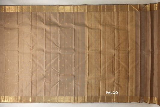 Greenish beige vintage Kanjivaram silk saree laid out, with small gold dots, gold borders and a patterned pallu on the right.