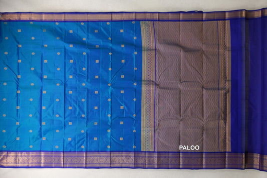 Unfolded Kanchipuram silk saree with a peacock blue body, small gold motifs, deep blue violet borders and a lattice-patterned pallu.