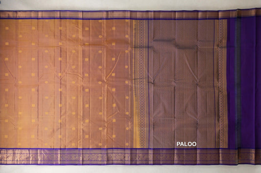 Lightweight Kanchipuram silk saree spread out, with a mustard body of small gold motifs, violet purple patterned borders and a lattice-patterned pallu.