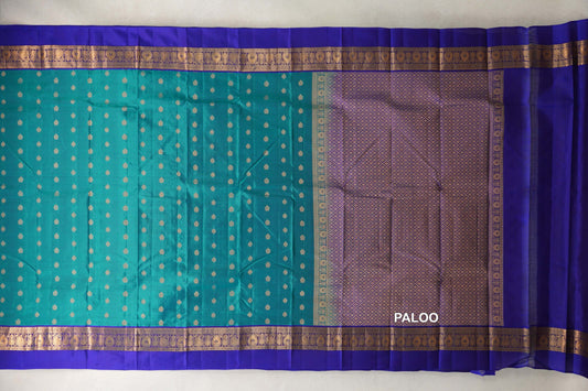 Lightweight Kanchipuram silk saree laid flat, with a peacock green body of small gold motifs, deep royal blue borders and a gold lattice pallu.