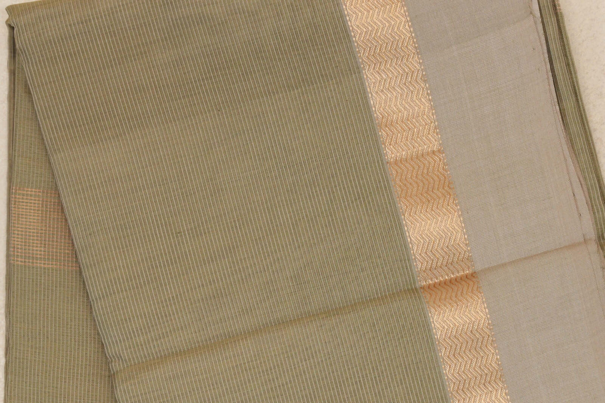 Folded light olive green Maheshwari silk cotton saree with fine stripes, a gold zari zigzag band and a broad light beige border.