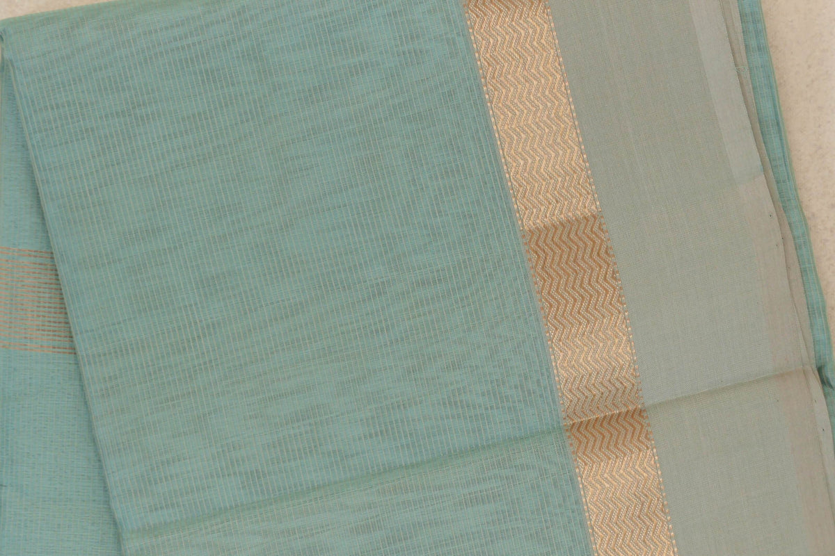 Folded sea green Maheshwari silk cotton saree showing a fine-lined body, light sandal beige border and shimmering gold zigzag stripe.