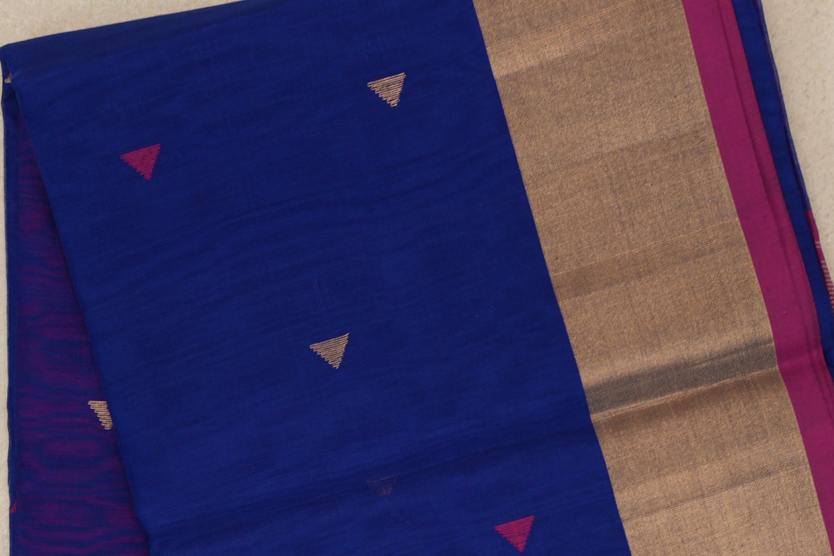 Folded Maheshwari silk cotton saree showing a bright royal blue body with small pink and gold triangles and a broad gold-toned border edged in rani pink.