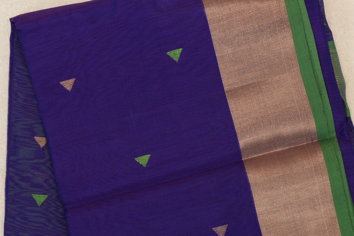 Folded deep violet Maheshwari silk cotton saree with small green and gold triangles, a broad copper-toned border and green selvedge.
