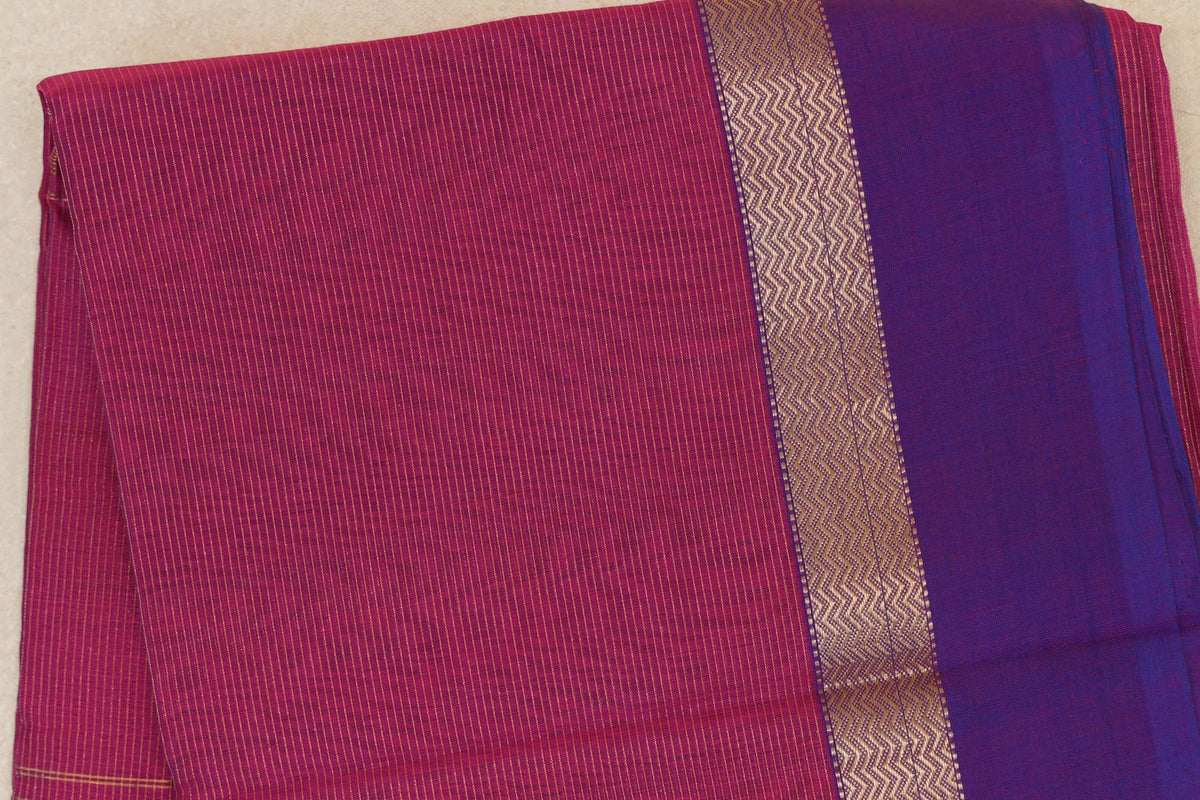 Folded Maheshwari silk cotton saree showing a finely striped Deep Rani Pink body beside a Violet Purple border with a gold zigzag band.