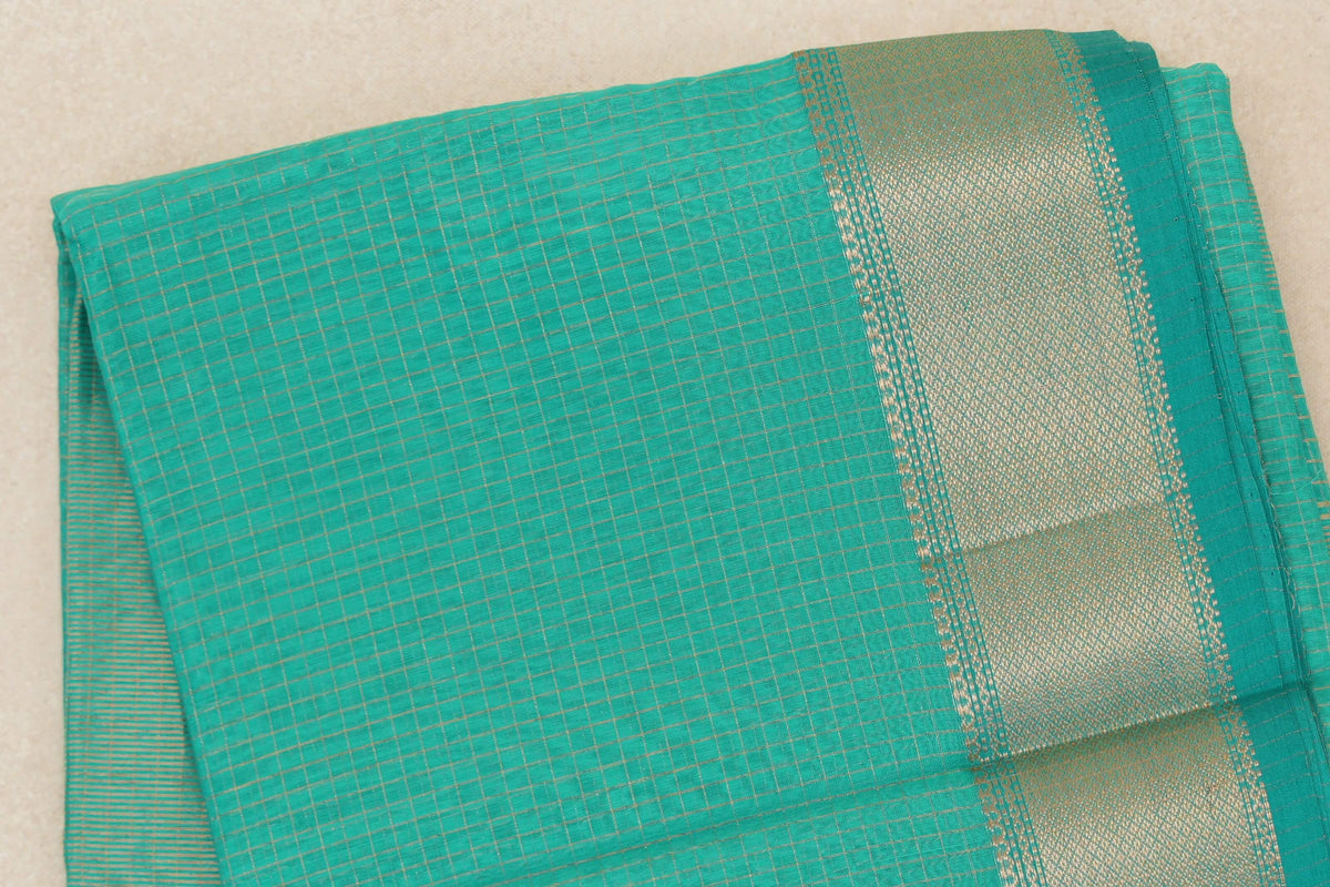 Folded turquoise green Maheshwari silk cotton saree with a fine gold check pattern and a broad, densely woven gold border.