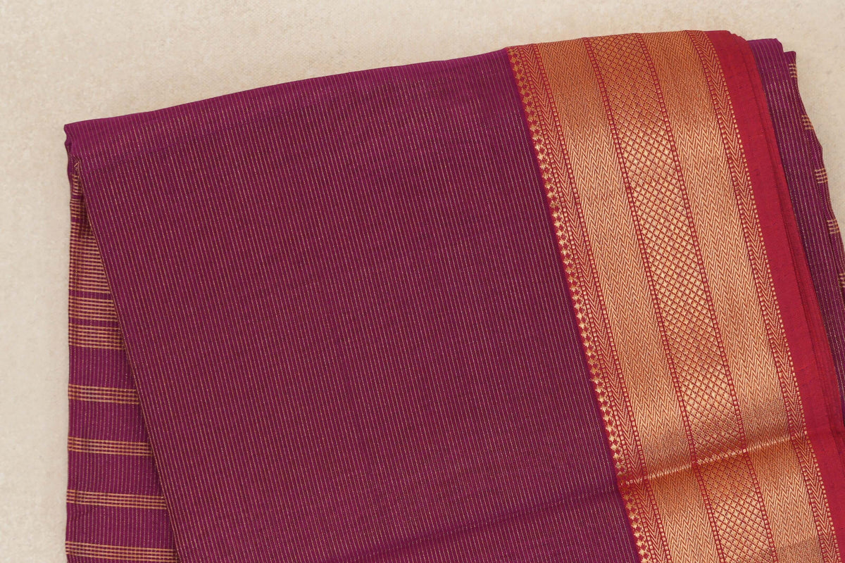Folded deep magenta Maheshwari silk cotton saree with fine gold stripes and a wide patterned border edged in Rani Pink.