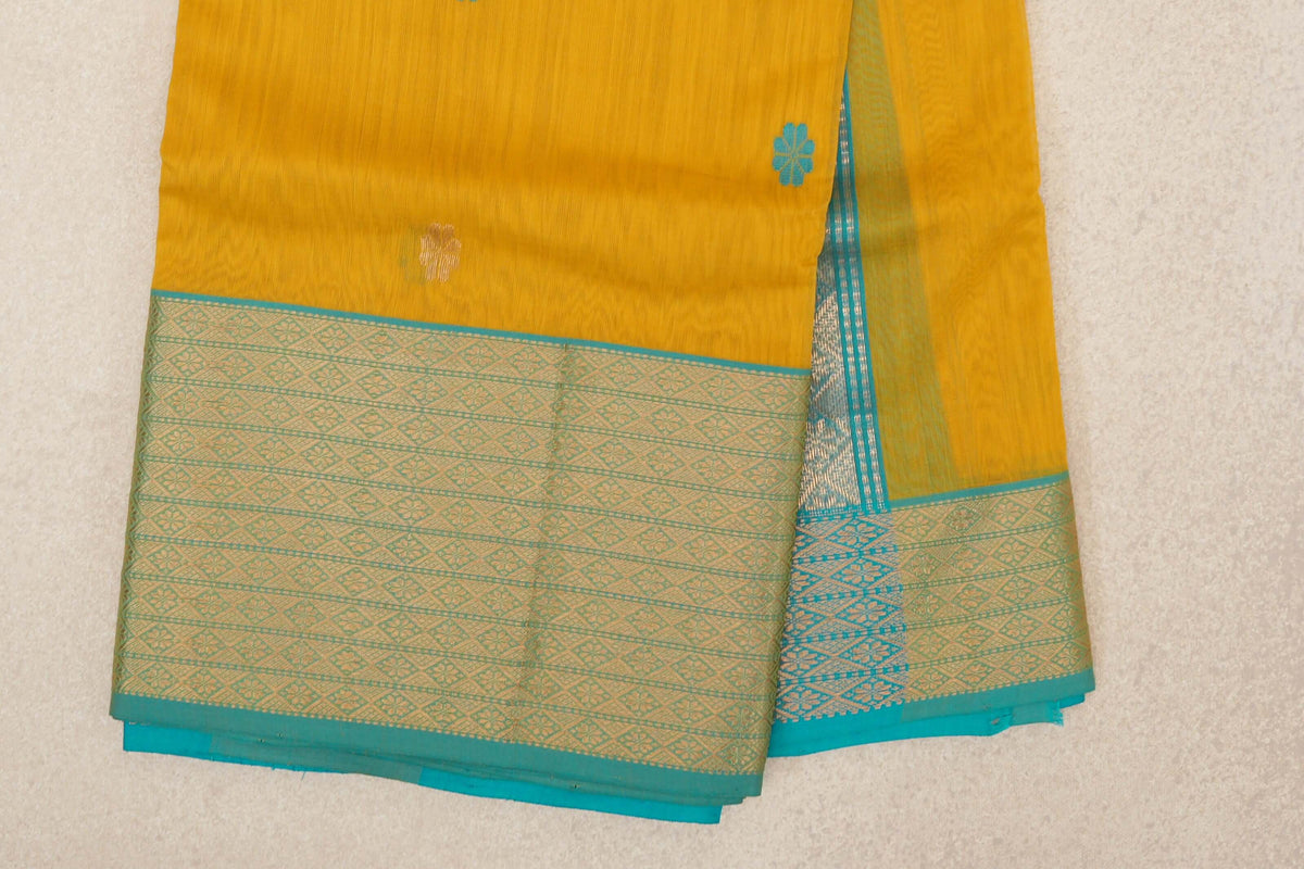Folded mango yellow Maheshwari silk cotton saree with small floral motifs and a wide turquoise blue border patterned with pale gold diamonds.
