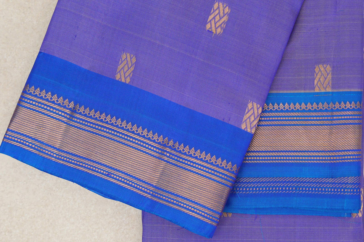 Folded lavender Kanchipuram silk saree with scattered gold motifs and a royal blue border with gold patterned stripes.