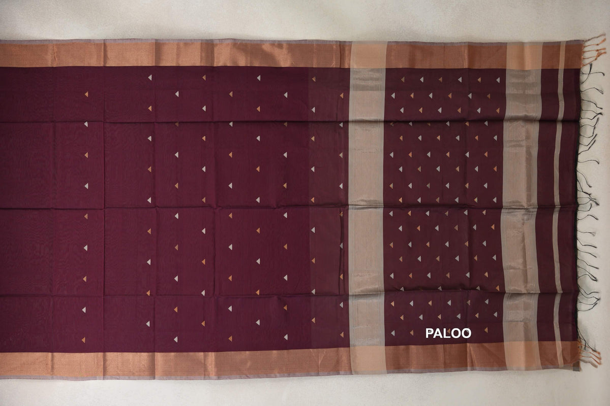 Deep wine maroon Maheshwari silk cotton saree laid out with small triangular motifs, warm-toned borders and a striped pallu with tassels.