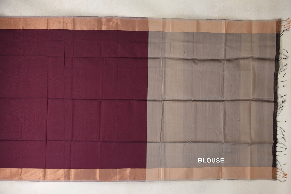 Unfolded Maheshwari silk cotton saree with a deep wine maroon body, dark beige blouse panel, pale borders and tassels along one edge.