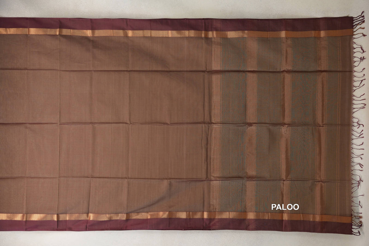Maheshwari silk cotton saree spread flat, showing a beige body, vertically striped pallu, magenta borders, gold-toned bands and tassels.