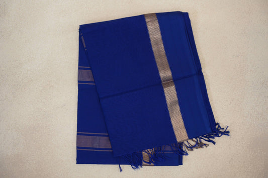 Folded Deep Royal Blue Maheshwari silk cotton saree with a metallic zigzag band, fine stripes and blue tassels.