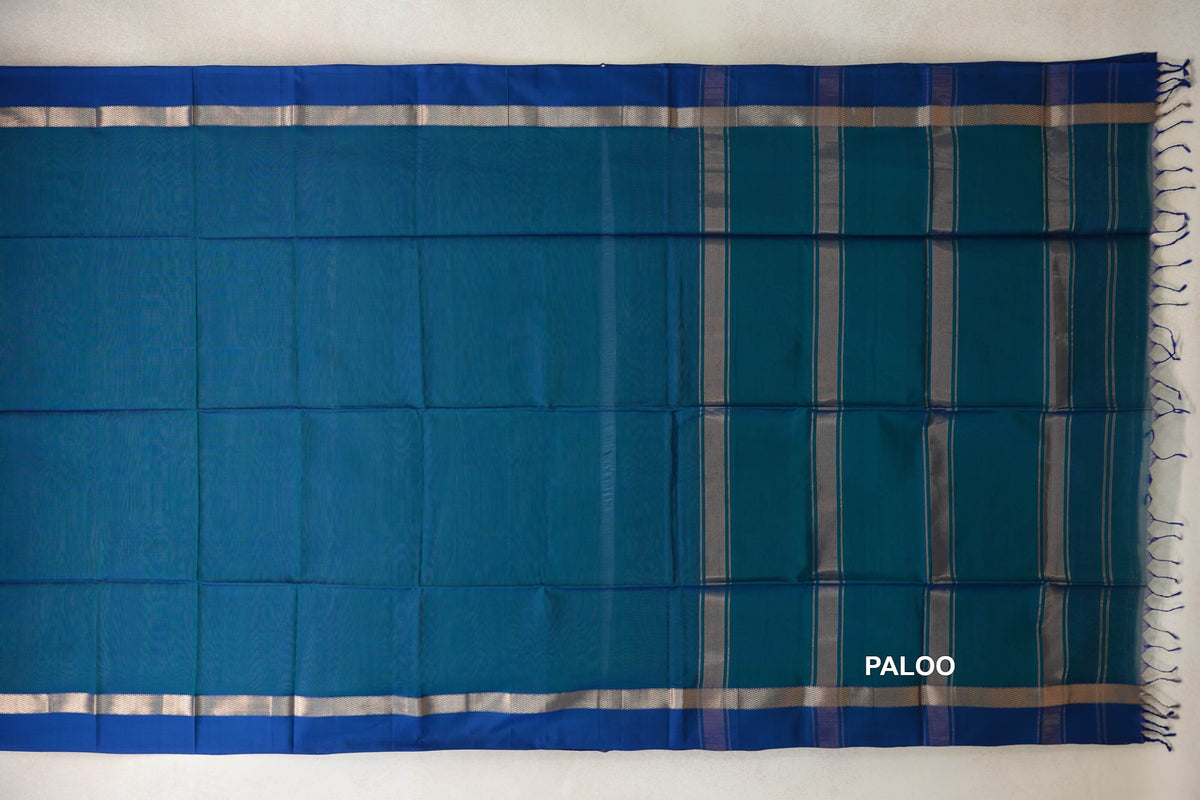 Peacock Blue Maheshwari silk cotton saree laid flat, showing a plain body, deep Peacock Blue borders and a striped pallu with tassels.