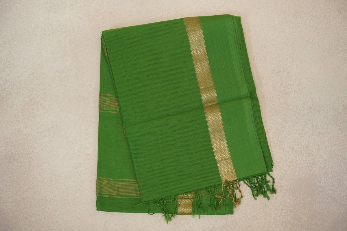 Folded leaf green Maheshwari silk cotton saree with a narrow gold zigzag stripe, fine striped border and green tassels.