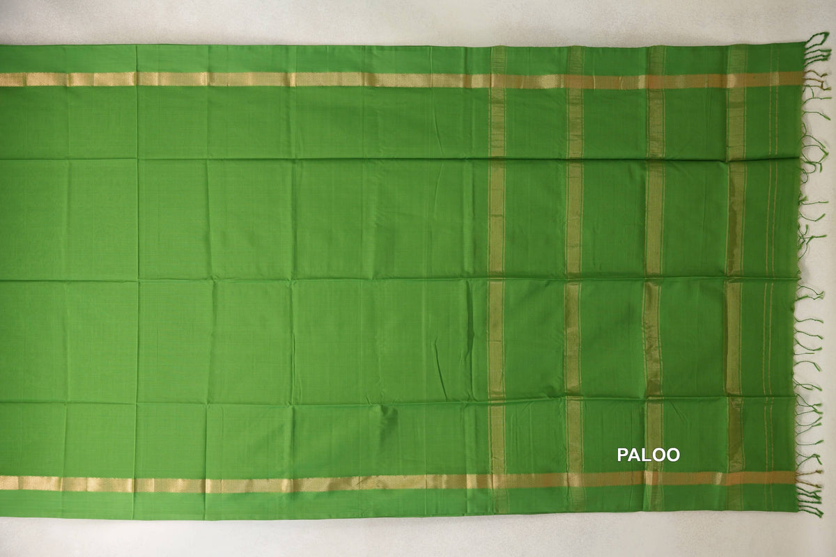 Leaf green Maheshwari silk cotton saree laid flat, with a plain body, gold-toned borders and a striped pallu with green tassels.