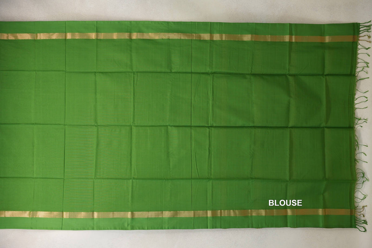Leaf Green Maheshwari silk cotton saree blouse section laid flat, with a plain body, narrow gold borders and tassels along one edge.