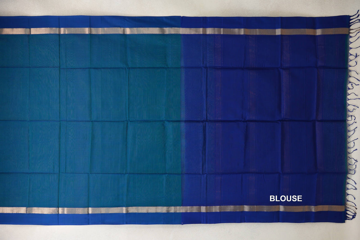Peacock Blue Maheshwari silk cotton saree laid flat, showing a plain body, deep blue blouse section, silver-toned border bands and tassels.