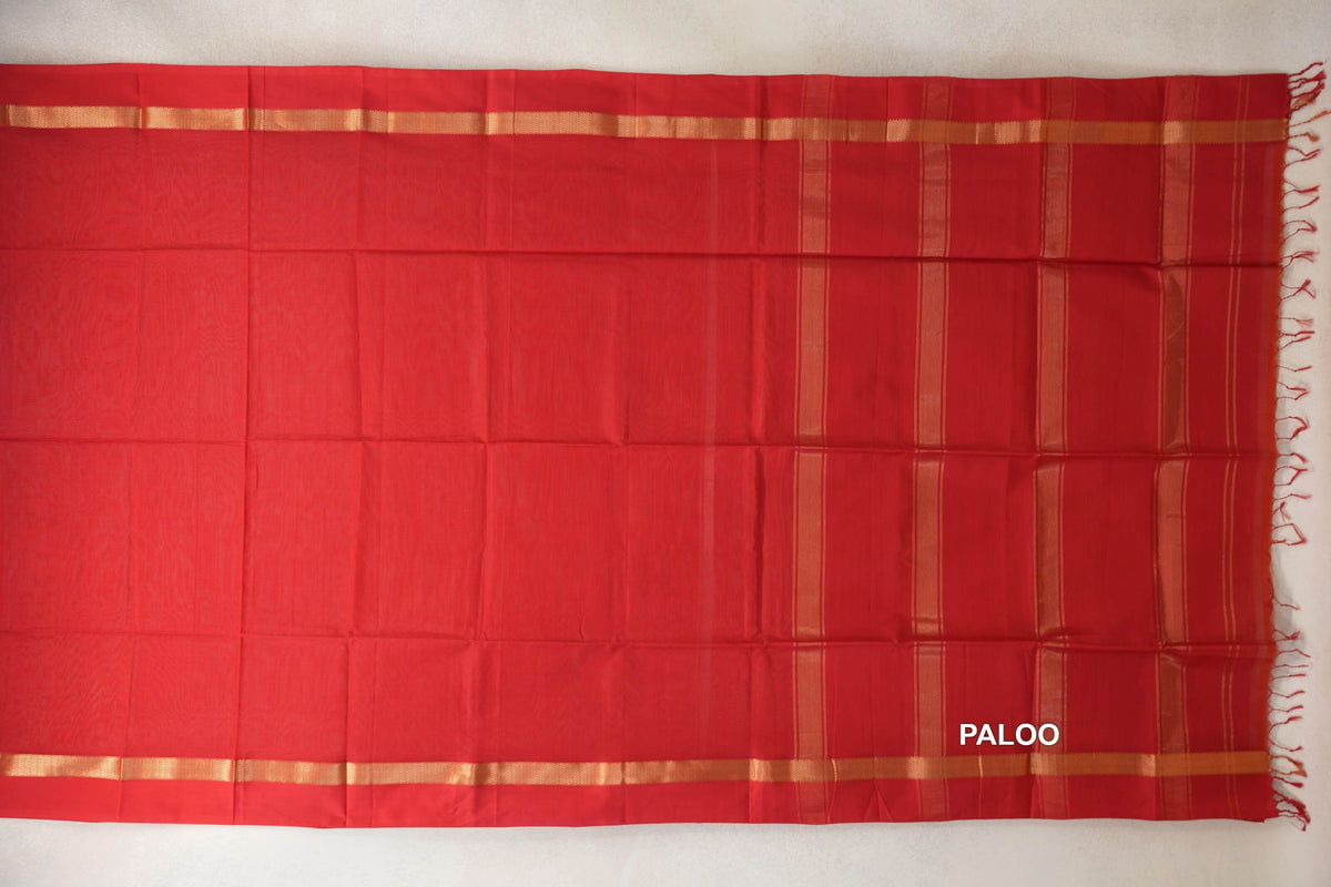Vermilion red Maheshwari silk cotton saree laid flat, with a plain body, gold-toned borders and a striped pallu with red tassels.
