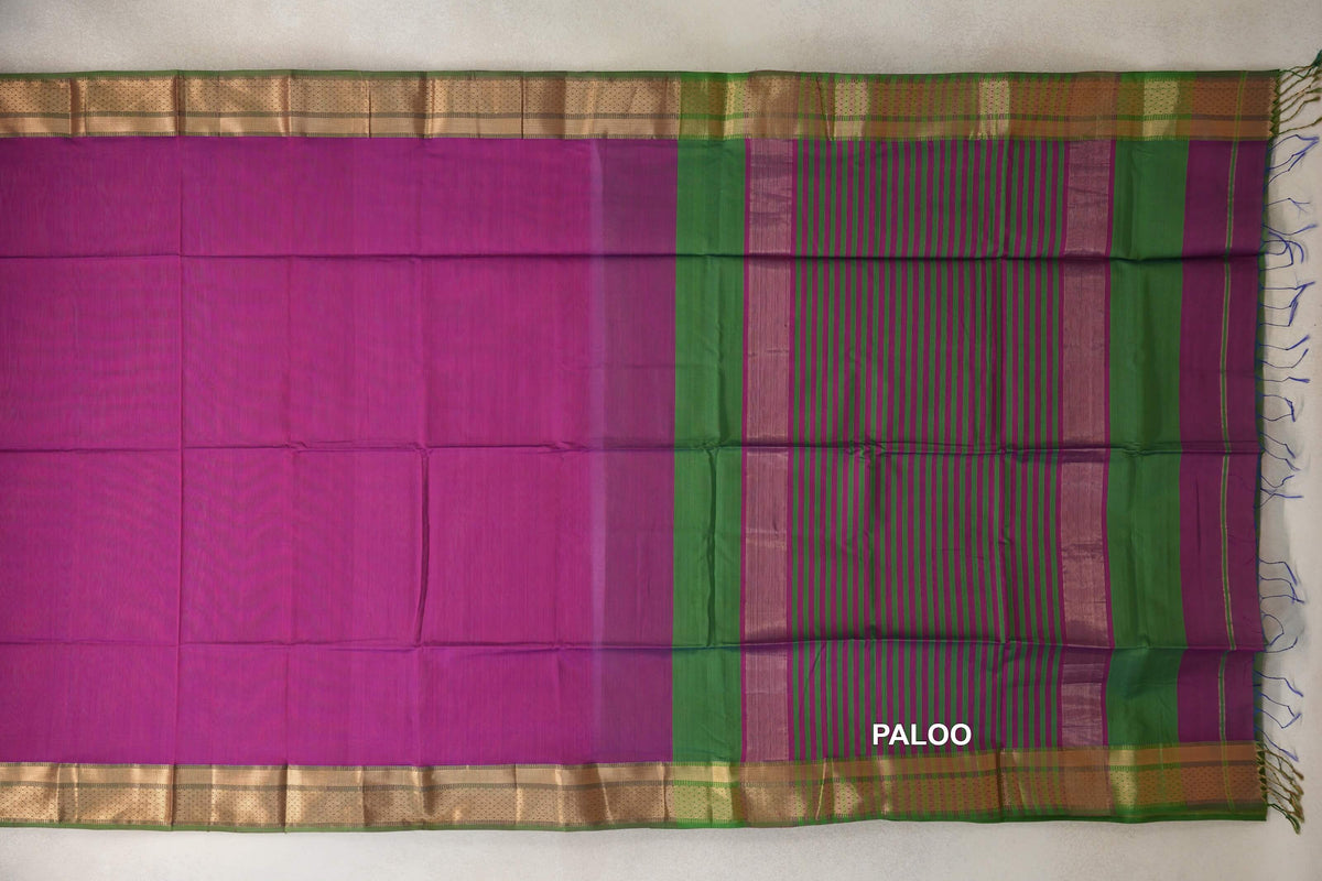 Dark magenta Maheshwari silk cotton saree laid flat, with leaf green and gold-toned borders and a striped magenta and green pallu with tassels.