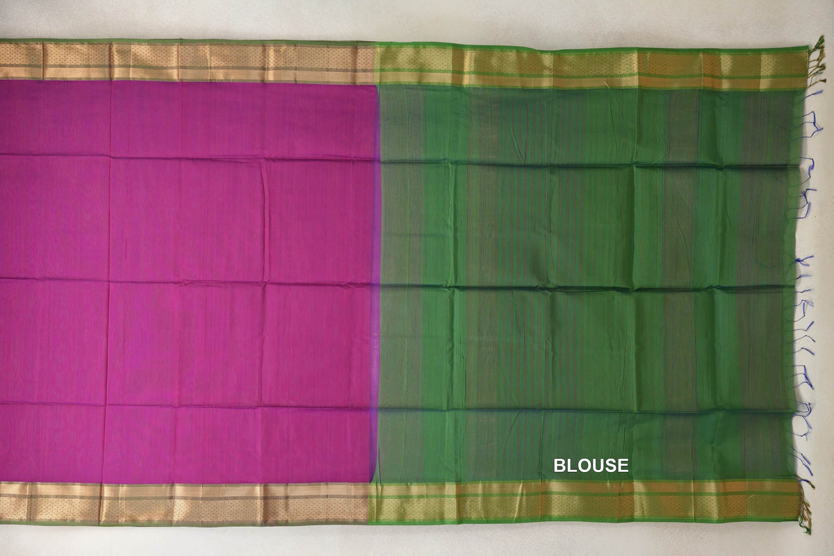 Unfolded dark magenta Maheshwari silk cotton saree beside its leaf green blouse fabric, with gold-toned borders and tassels at the edge.
