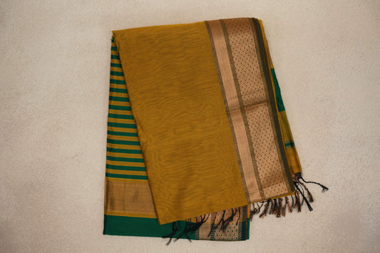 Folded mustard yellow Maheshwari silk-cotton saree with a gold-toned patterned border, emerald green and mustard striped pallu, and tassels.