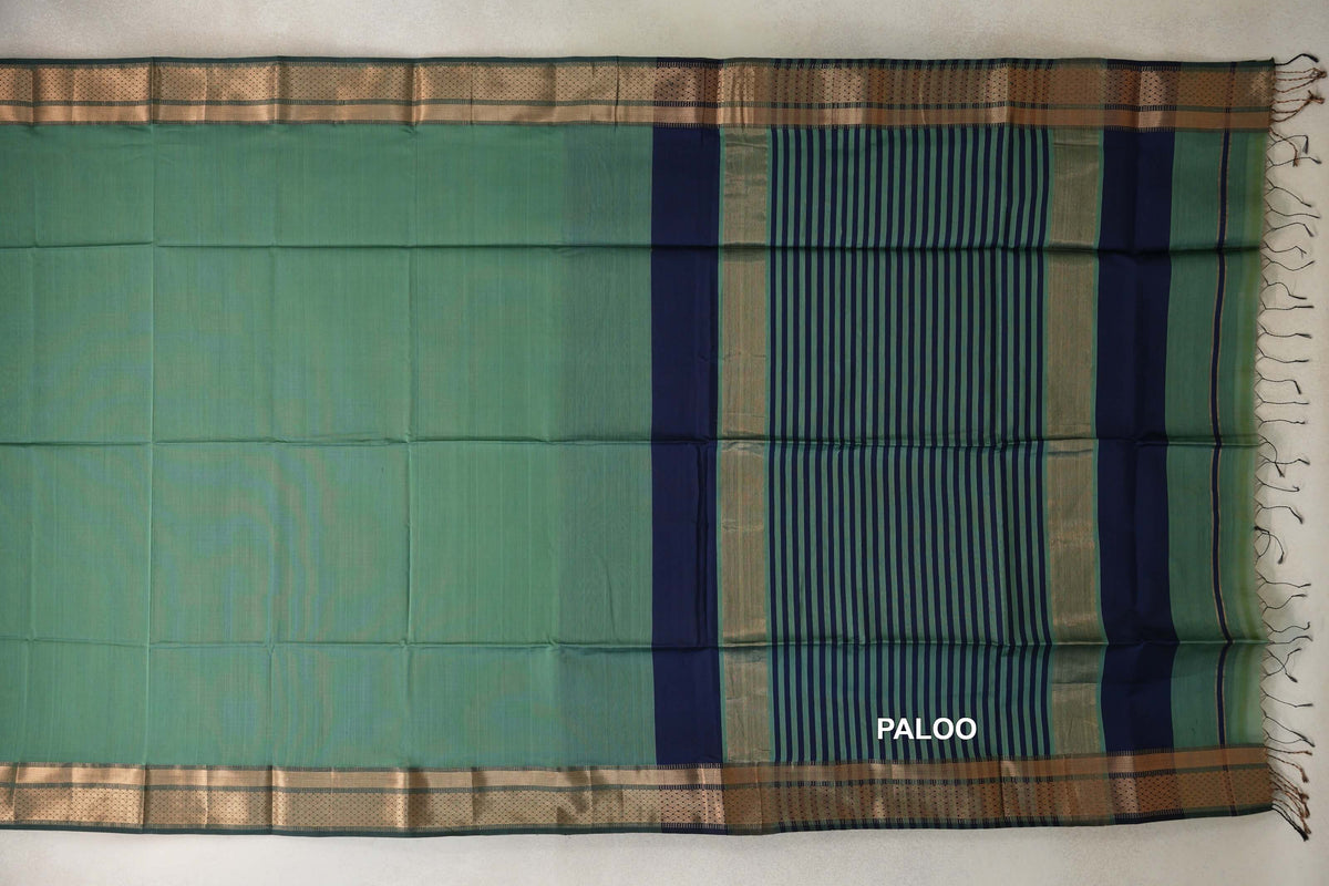 Sea green Maheshwari silk cotton saree laid flat, showing gold zari borders and a navy blue and sea green striped pallu with tassels.