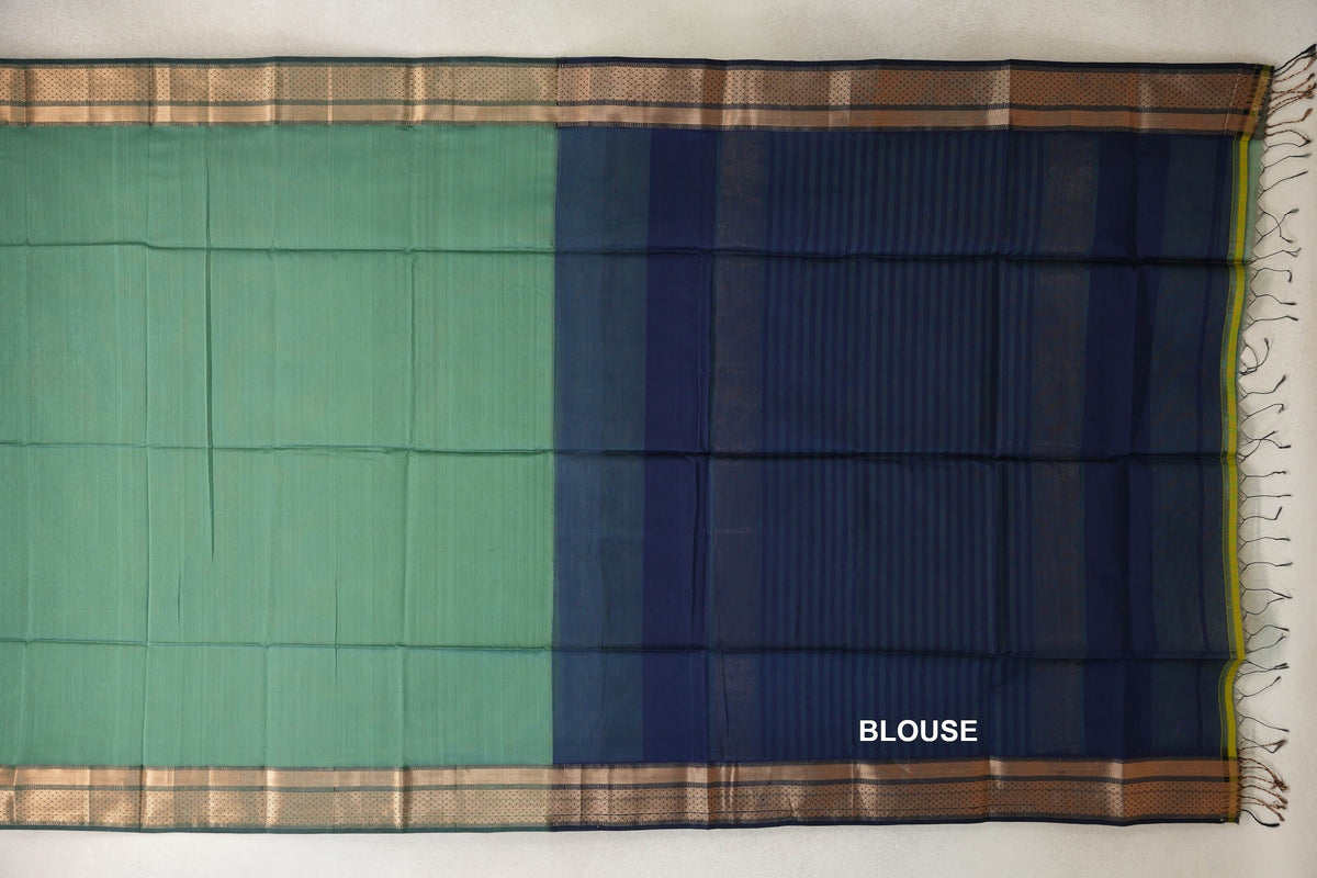 Laid-out sea green silk cotton saree with gold zari borders, beside a striped navy blue blouse section with tassels at the edge.