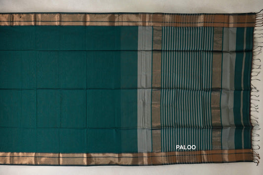 Peacock green Maheshwari silk cotton saree laid flat, with patterned borders and a dark peacock green pallu striped in silver grey, ending in tassels.