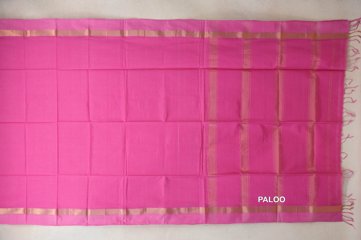Bright Rani Pink Maheshwari silk cotton saree spread out, with pink borders, gold-toned bands, a striped pallu and tassels at the end.