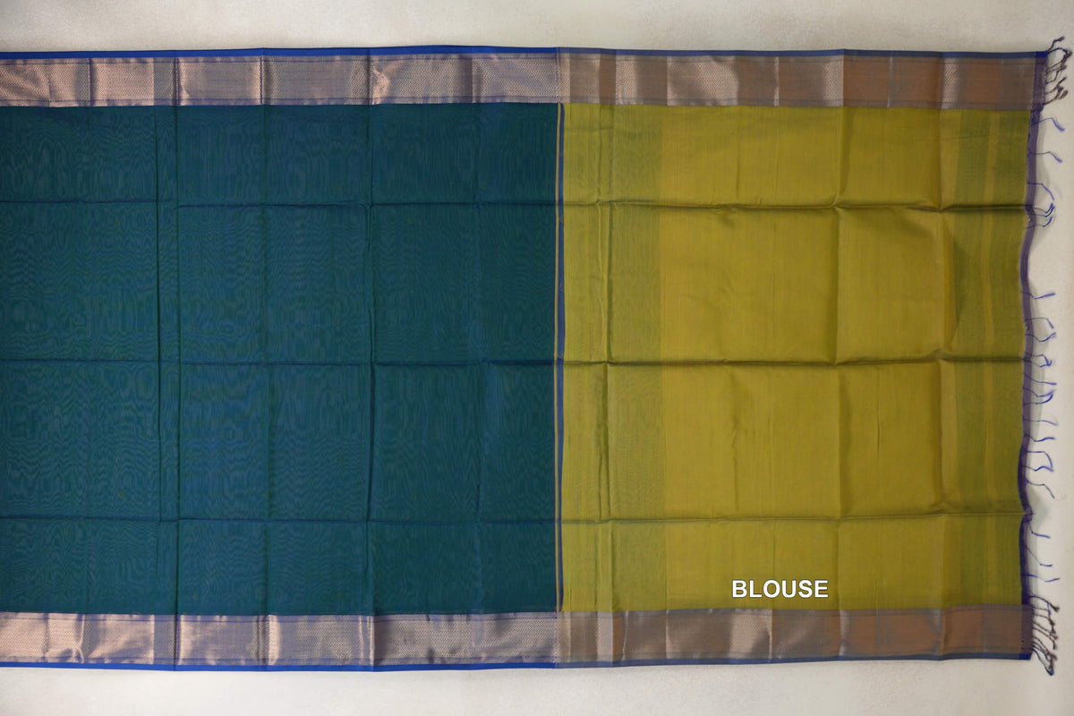 Maheshwari silk cotton saree laid flat, showing a peacock green body beside a mehendi green blouse section, with royal blue-edged borders and tassels.