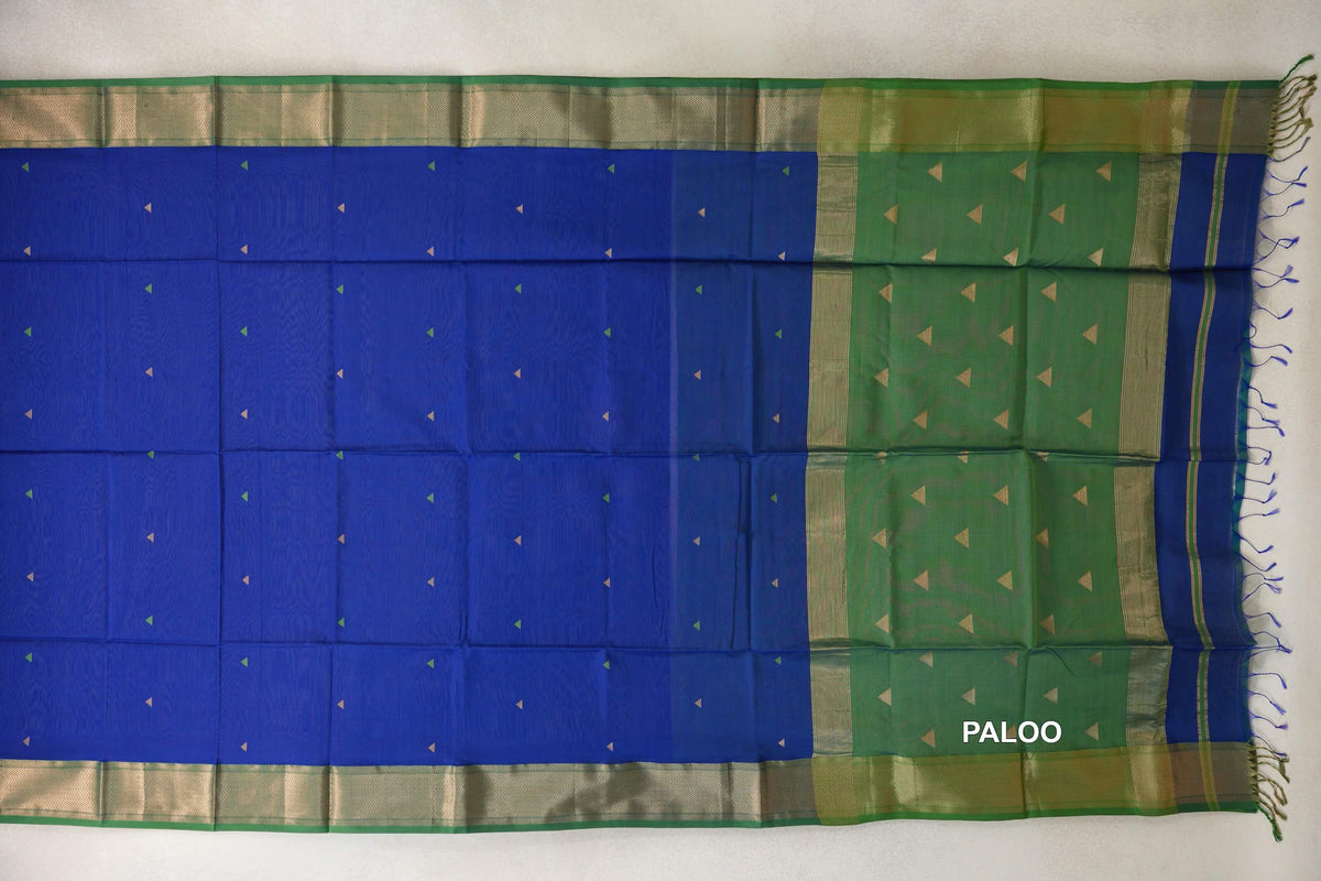 Maheshwari silk-cotton saree spread flat, with a royal blue body, small triangle motifs, leaf green borders and pallu, and tassels.