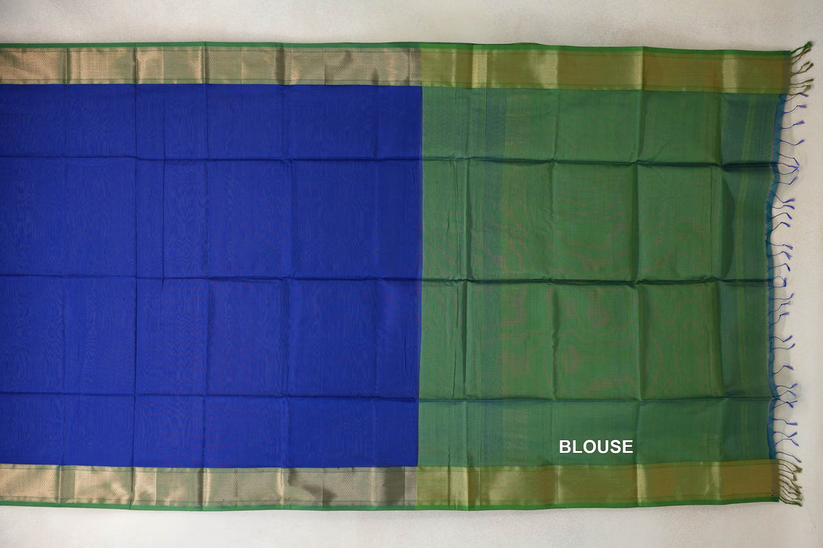 Maheshwari silk-cotton saree spread flat, showing a royal blue body, leaf green blouse piece, patterned borders and tassels at one end.
