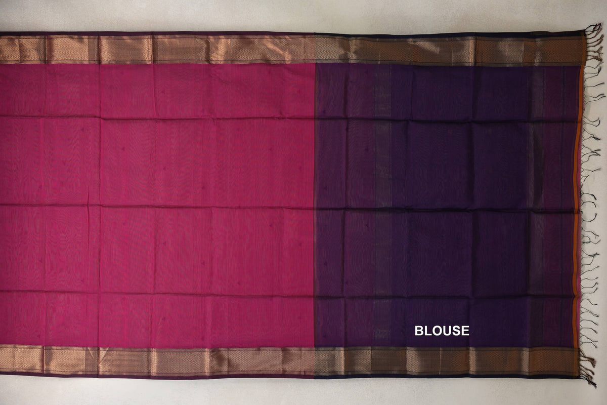 Silk cotton saree laid flat, with a Deep Rani Pink body, a Deep Purple blouse section, zigzag-patterned borders and tassels at one end.