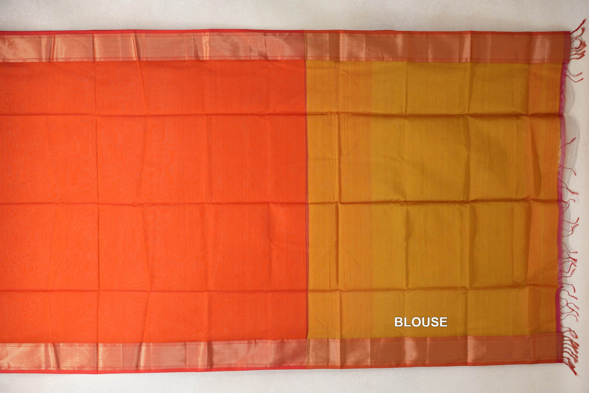 Maheshwari silk cotton saree laid flat, showing a reddish orange body, patterned orangish red borders and a mustard yellow blouse piece with tassels.