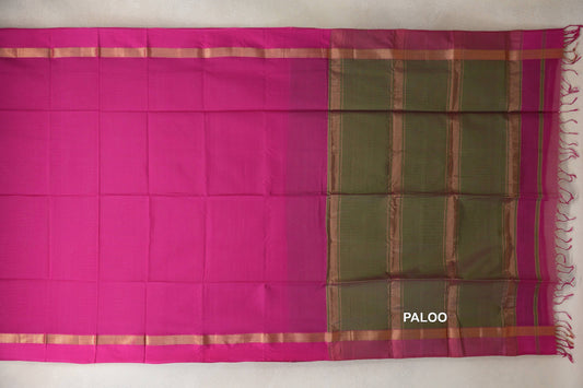 Rani pink Maheshwari silk cotton saree laid flat, with narrow gold-toned borders, an olive green striped pallu and pink tassels.