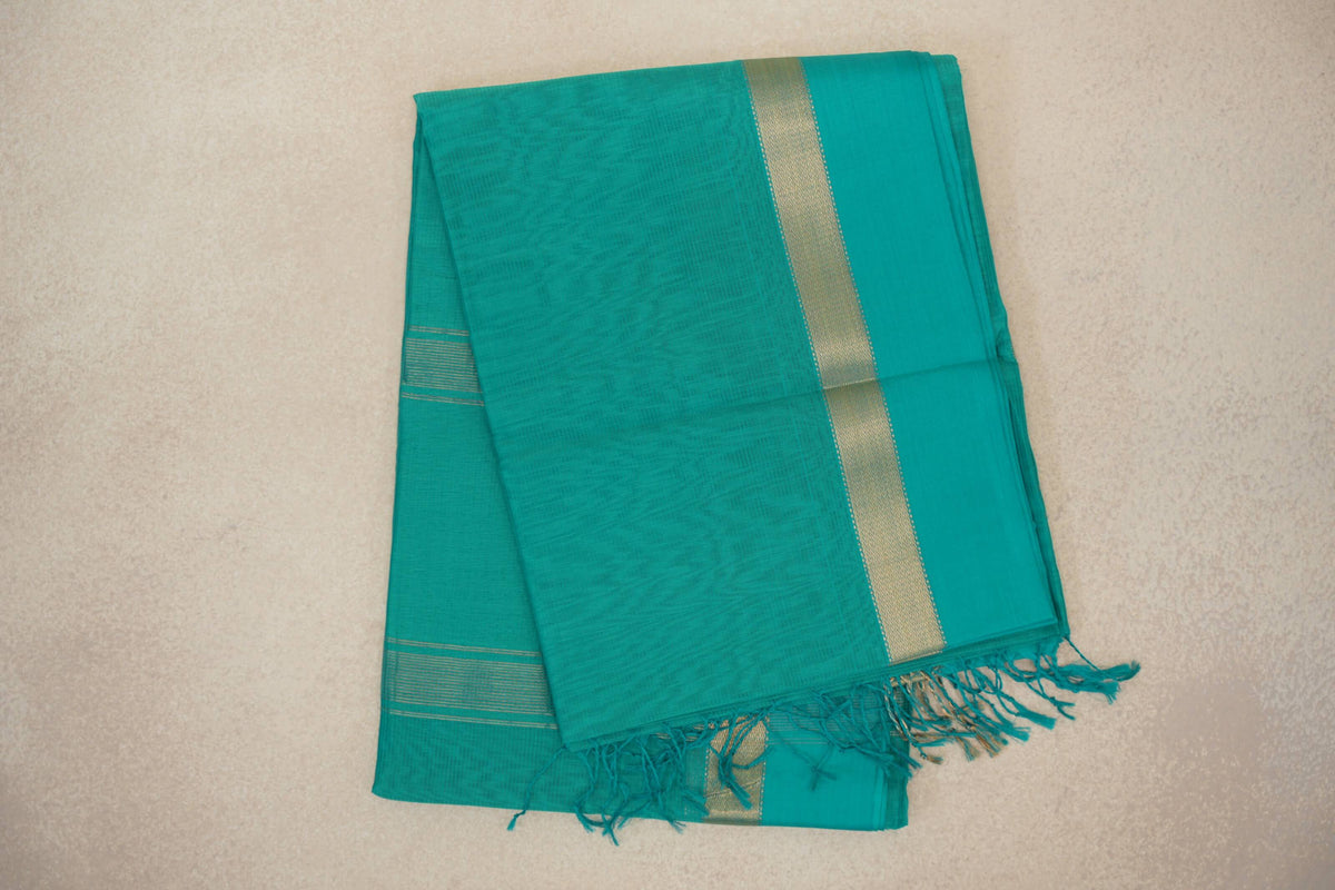 Folded bright aqua green Maheshwari silk cotton saree with a subtly textured body, gold-toned border stripe and tasselled edge.