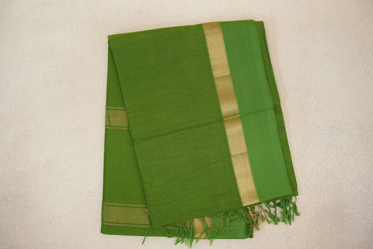 Folded leaf green Maheshwari silk cotton saree with fine checks, a gold zigzag-patterned border, narrow gold stripes and green tassels.